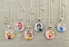 four different disney princess necklaces hanging from chains