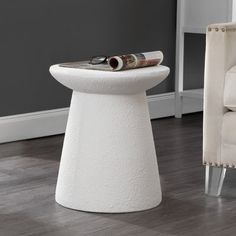 a white table sitting on top of a hard wood floor next to a beige chair