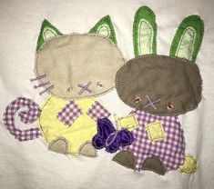 two patchwork cats are sitting next to each other on a white t - shirt