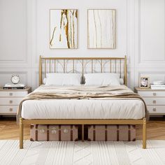 a bedroom with white walls and wooden flooring has a gold metal bed frame, two nightstands, and paintings on the wall