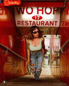 a woman is walking down the stairs in front of a restaurant sign that says wo hop