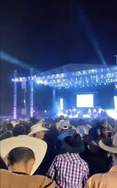 a large group of people at a concert with hats on their heads and lights in the background