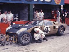 a man working on a race car in front of a group of men standing around