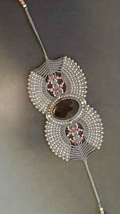 a silver necklace with pink and white beads hanging from it's side on a gray surface