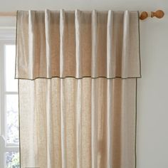 the curtain is hanging on the wall next to the window with two wooden knobs