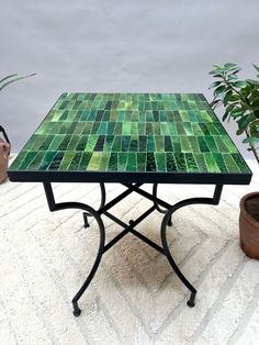 a green tiled table sitting next to a potted plant