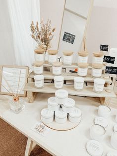 the table is full of all kinds of creams and candles for sale in front of a mirror