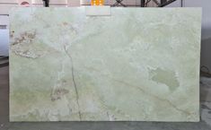 a large green marble slab in a warehouse with other items on the floor behind it