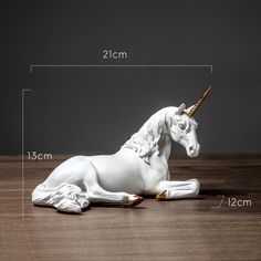 a white unicorn figurine sitting on top of a wooden table next to a ruler