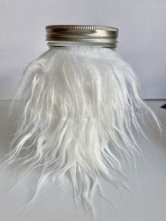 a jar filled with white feathers sitting on top of a table