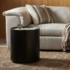 a white couch sitting next to a wooden table on top of a carpeted floor