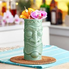 a green vase with flowers in it sitting on a table