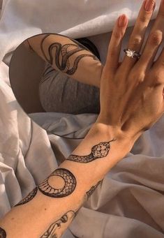 a woman's arm with a snake tattoo on it and a diamond ring in the middle