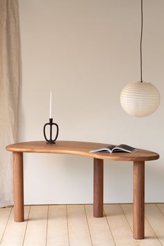 a wooden table with a book on it next to a candle and a light bulb