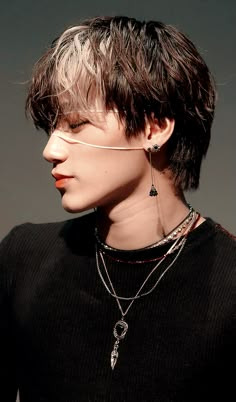 a woman with short hair wearing a black shirt and silver necklaces on her neck