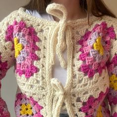 a close up of a person wearing a crocheted jacket with flowers on it