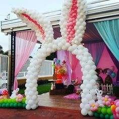 an outdoor party with balloons and decorations on the ground, including a large bunny balloon arch