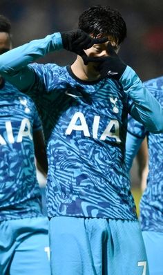 the soccer players are wearing blue uniforms and covering their eyes with black gloves while standing together