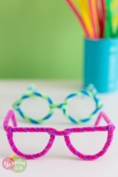 two plastic glasses sitting on top of a table next to a cup with pencils in it