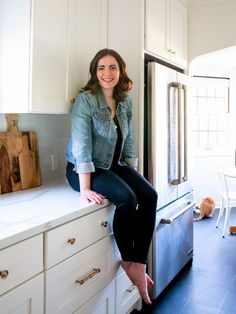 a woman sitting on top of a kitchen counter