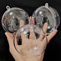 two clear glass balls held in the palm of a person's hand on a black background