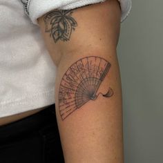 a woman's arm with a tattoo on it that has a fan in the middle