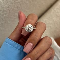 a woman's hand holding a ring with a diamond on it and the middle finger