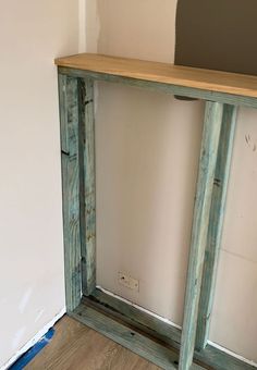 a wooden shelf sitting on top of a hard wood floor next to a white wall