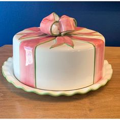 a pink and white cake with a bow on top