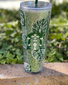 the starbucks cup is decorated with green glitters and has a straw sticking out of it