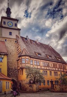 an old building with a clock tower on the top of it's roof and people walking around