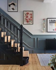 a staircase with pictures on the wall and wooden flooring next to it, along with a rug