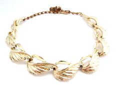 A vintage modernist style leaf design adjustable length dog collar to choker length necklace by BSK.  Formed from gold tone metal, set to the front with  nine leaf shaped panels, set on a gold tone belcher style chain. Adjustable length hook fastener. The style of this necklace allows it to be worn against the neck dog collar style to a short length choker. Circa 1950's - 60's     Length of necklace approx 31cm - 42cm, so dog collar to short choker in length.     Adjustable length lobster hook c Retro Gold Adjustable Choker, 50s Jewelry, 60s Jewelry, Length Necklace, Hook Clasp, Choker Necklaces, Leaf Shapes, Gold Tone Metal, Leaf Design