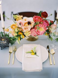 the table is set with flowers, candles and place settings for an elegant dinner party