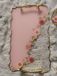 a pink and gold plate with flowers on it sitting on a white furnishing