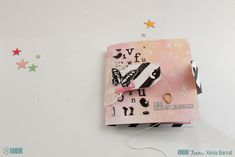 an altered book with butterflies and stars on the wall next to it is decorated in pink, black, and white