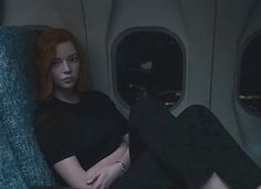 a woman with red hair sitting on an airplane