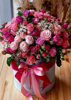 a large bouquet of pink roses in a white box on a wooden table next to a dog