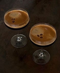 two glasses filled with liquid sitting on top of a table next to each other in front of a black background