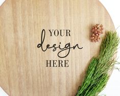 a wooden sign with the words your design here on it next to a sprig of grass