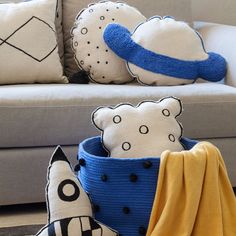 pillows and blankets are sitting on the floor in front of a couch with a rocket ship pillow