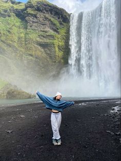 a woman standing in front of a waterfall