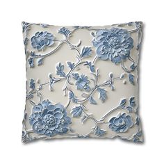 a blue and white pillow with flowers on it's side, in front of a white background