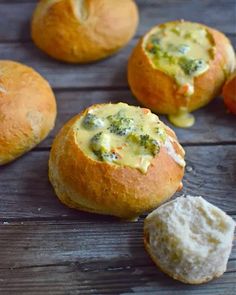 several rolls with broccoli and cheese in them on a wooden table next to some bread