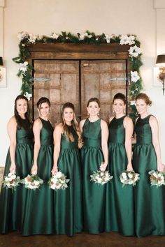 a group of women standing next to each other wearing green dresses and holding bouquets