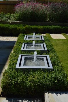 three water fountains in the middle of a garden