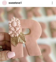 a person holding up a pink letter with flowers on it