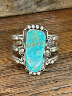 This Eye-Catching Turquoise Sterling Silver Cuff Bracelet is made by Navajo Silversmith Artist MM with highly sought after Kingman Turquoise.  This huge free form shaped stone has exquisite vibrant coloring with stunning copper vein accents and is set into a serrated sterling silver bezel and surrounded by curved designs adorned with 'raindrop' accents.  This show-stopper bracelet would make the perfect gift for yourself, a friend or spouse for any special occasion! ★Specifics★ Metal: Sterling S Western Turquoise Bangle Cuff Bracelet, Western Style Turquoise Bangle Cuff Bracelet, Turquoise Concho Bohemian Cuff Bracelet, Bohemian Turquoise Cuff Bracelet With Concho, Bohemian Turquoise Concho Cuff Bracelet, Turquoise Bohemian Cuff Bracelet With Concho, Handmade Turquoise Western Cuff Bracelet, Western Turquoise Bracelet With Patina, Turquoise Bracelet Cuff