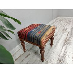 a small wooden bench sitting on top of a hard wood floor next to a potted plant