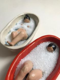 there are two small figurines in the bathtub, one is laying down